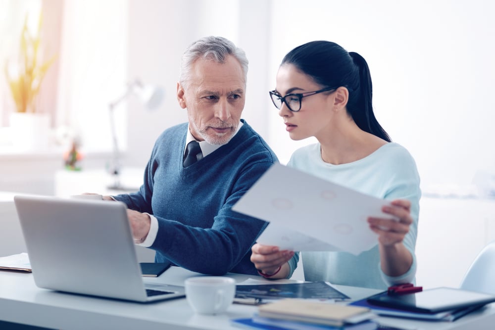 business man and woman on laptop with paper